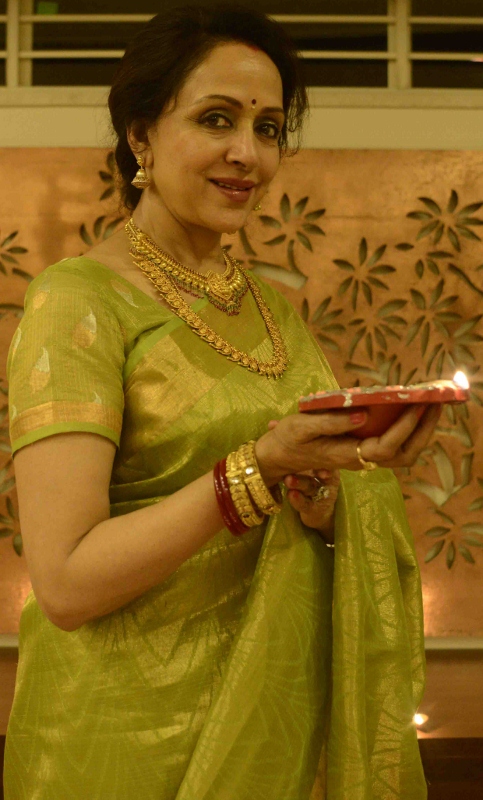 Hema Malini holds up a diya as she poses in front of the camera after a grueling 18-hour day